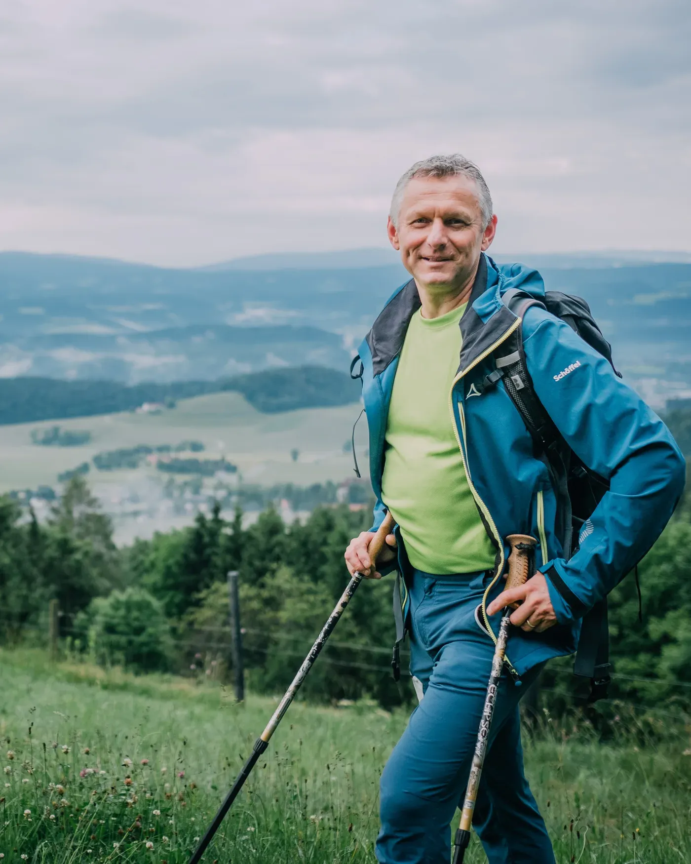 Andreas Kohlbacher mit Wanderstöcken vor den Hügeln der Weststeiermark