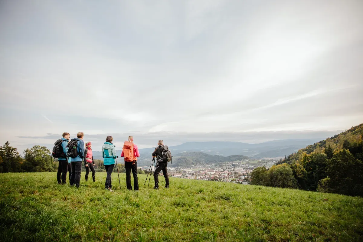 Wandergruppe blickt von einer Anhöhe über das Tal der Weststeiermark